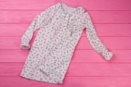 Peasant style girls nightgown on pink wooden background. Adorable ruffles and flowers. Kids sleepwear.の写真素材