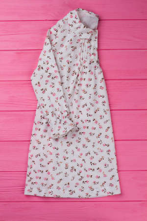 Cotton nightie with floral design. Ruffle cuffs and rounded collar. Sleepwear collection item on pink wooden display.の写真素材