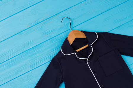 Shirt on wooden hanger. Navy garment with breast pocket and rounded collar. Fashion clothing background.の写真素材