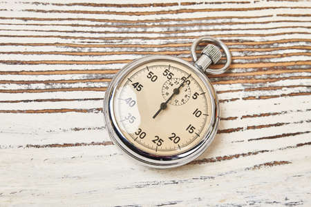 Retro stopwatch on rustic wooden background. Analog timing device for athletes and trainers.