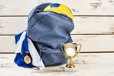 Young sportsmans football trophy and equipment. Backpack and soccer ball. Sports and winners.