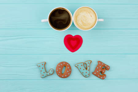 Couple of cups with coffee and cappuccino. Word love from baked cookies and red heart. Happy...