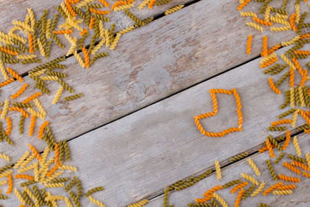 Colorful pasta on old wooden table. For italian food lovers. Italian cuisine concept. Valentines Day composition on old wooden background.の写真素材