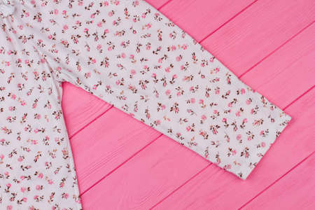 Close up on pajama pants. Sleeping garment decorated with flower pattern. Pink wooden shelf of a...