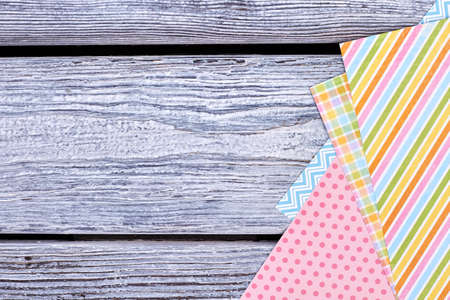 Colorful patterned paper and copy space. Sheets of paper for handmade craft on rustic wooden background, top view. Material for Easter handicraft.の写真素材