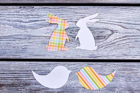 Cut out paper rabbits and birds. Papercut animalistic silhouettes. Color patterned paper figurines. Easter festive preparations.の写真素材