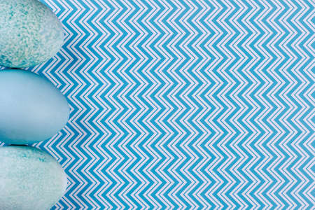 Painted Easter eggs on patterned background. Blue Easter eggs on blue zigzag pattern background and copy space. Easter holidays concept.の写真素材