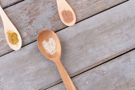 Variety of spices in wooden spoons. Wooden spoon with rice in a shape of heart on old wooden background, space for text.の写真素材