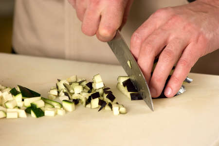 Courgette dicing closeup. Male hands dicing a courgette into small pieces, close-up.の写真素材