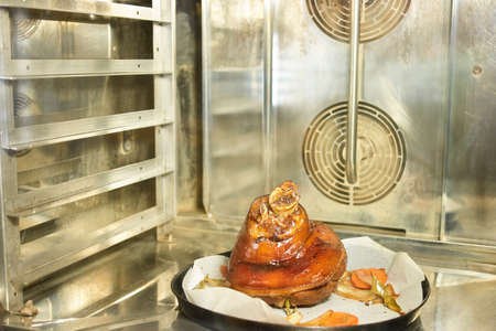 Pork knuclke with side dish on baking paper. Pork knuclke with side dish on baking paper. Dish on black plate. Pork knuclke in oven.の写真素材