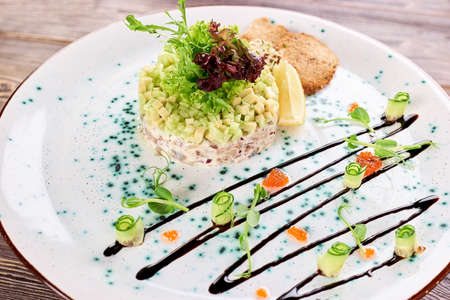 Avocado with toasts in tartar sauce with Belgian herring. Delicious perfectly looking salad served in restaurant, close up.の写真素材