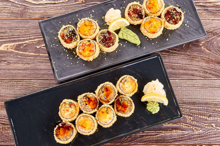 Two plates of juicy unagi furay sushi, top view. Sets of sushi with white ginger, wasabi and lemon.の写真素材