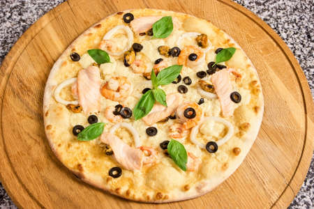 Pizza with seafood, olives and basil leaves. Round uncut pizza.の写真素材