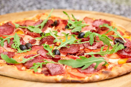 Close up salami pizza with olives and arugula leaves. Baked pizza with arugula, close up.の写真素材