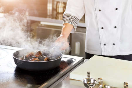 Shellfish mussels cooking in pan. Chef frying mussels on pan, steaming mussels.の写真素材