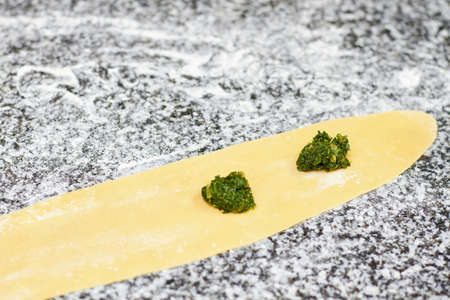 Two little piles of greens on dough sheet. Dough and greens.の写真素材