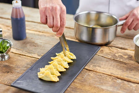 Putting raviolis in a row. Chef putting raviolis using kitchen tongs.の写真素材