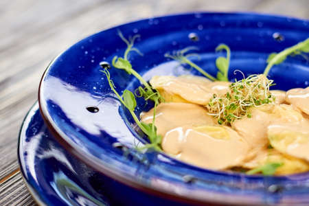 Close up dumplings with creamy sauce and sprouts. Dish with creamy sauce and greens.の写真素材