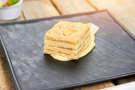 Napoleon cake on black square plate. Side view napoleon layers.