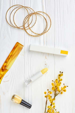 Cosmetics and jewelry, wooden background. Decorative cosmetics, comb, bracelets and pussy willow twig. Beauty and femininity concept.の写真素材