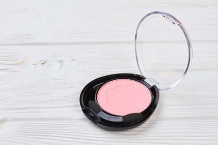 Pink color eyeshadow in plastic container. Face powder blusher on white wooden background. Make up and visage concept.の写真素材