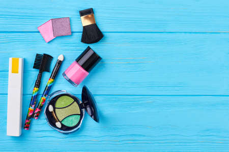 Fashion cosmetics items, copy space. Decorative cosmetics products on blue wooden background. Female beauty objects.の写真素材