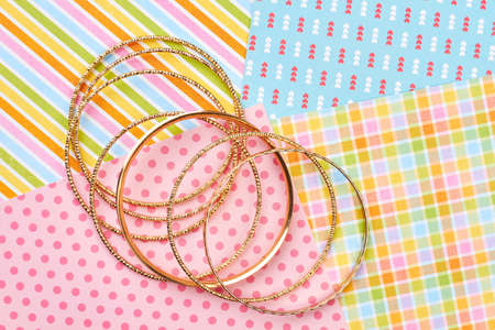Set of golden bracelets, colorful background. Female bangles on patterned paper background. Woman...