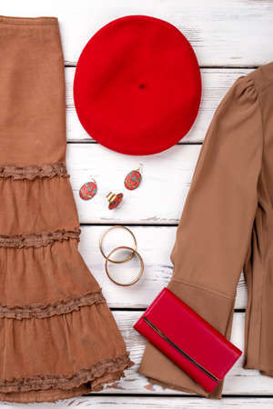 Red french beret and accessories. Red purse, clothes and jewelry on wooden background. Set of female elegant clothing.の写真素材