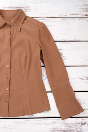 Women blouse shirt, wooden background. Brown color formal shirt for woman. Female brand outfit on sale.の写真素材