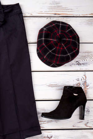 Women black trousers and boots. Female black ankle boots and cap on white wooden background. Feminine fashion background.の写真素材