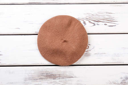 Beige color beret for women. Female french beret on white wooden background. Stylish headgear for woman.の写真素材