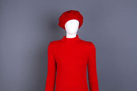 Mannequin in red beret and sweater. Red turtleneck modern pullover on mannequin, grey background. Feminine stylish clothes and accessories.の写真素材