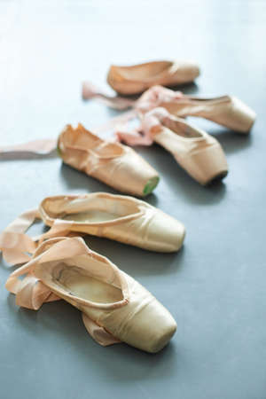Ballet pointe shoes on the floor. Old used ballet slippers for girls on grey background.の写真素材