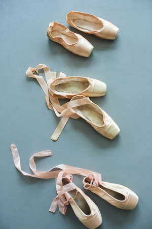 Old pointe shoes, top view. Three pairs of slippers for ballet on grey background. Ballet shoes still life.の写真素材