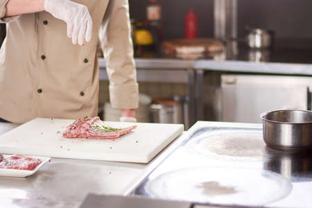 Chef processing ribs with spices. Cropped image of chef cooking lamb ribs at european restaurant.の写真素材