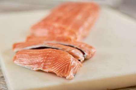 Sliced raw salmon on cutting board. Fresh salmon fillet on cutting board. Restaurant of seafood.の写真素材