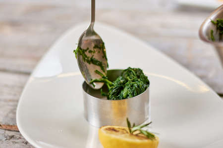 Putting green salad in stainless dish. Preparing of delicious food at restaurant. Food and culinary concept.の写真素材