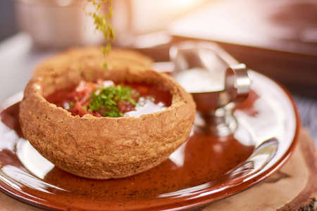 Red beetroot soup in bread pot. Red borshch with beef meat in pot of bread. Restaurant of ukrainian food.の写真素材