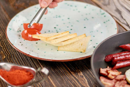 Chef putting english breakfast on plate. Chef serving plate in restaurant with english breakfast. Cook preparing dish.の写真素材
