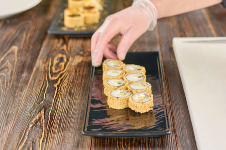 Chef placing sushi rolls on plate. Unagi sushi rolls set on traditional japanese dish. Chef at work, sushi bar.の写真素材