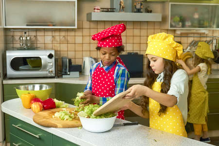 Kids cooking at kitchen table. Fruit and vegetables.の写真素材