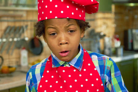 Upset kid in chef uniform. Sad black boy.の写真素材