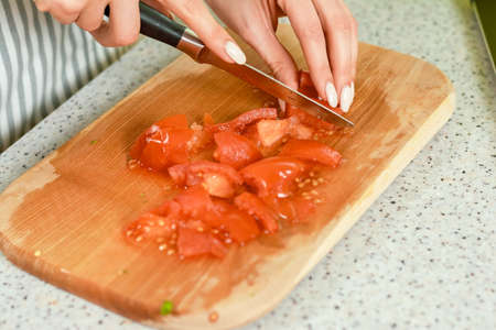 Hands cutting tomato close up. Pieces of juicy red vegetable.
