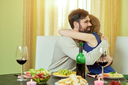 Couple at dinner table hugging.の写真素材