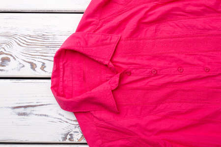 Collar of red womans shirt. Close up pink shirt on white wooden table.の写真素材