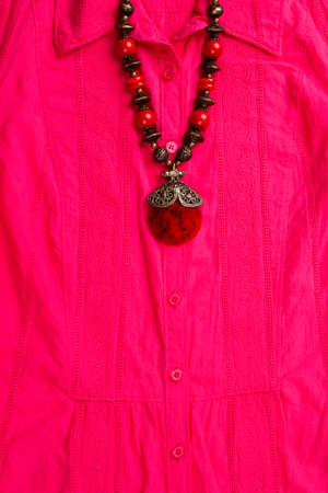 Jewelry on pink shirt. Stylish necklace, decorated with amber and silver beads.の写真素材
