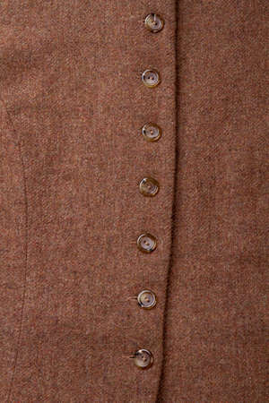 Buttons on brown woolen clothes. Close up column of buttons, vertical view.