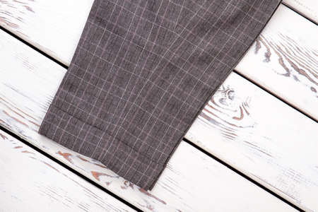 Close up grey trouser-leg. Bright beige white wooden desks surface background.の写真素材