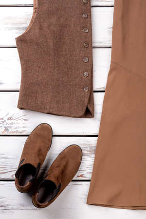 Close up brown women outfit. Vertical photo. White wooden desks surface background.の写真素材