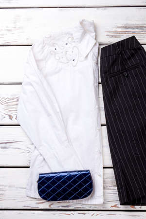 White decorated women blouse and blue wallet. Black striped skirt with pocket.の写真素材